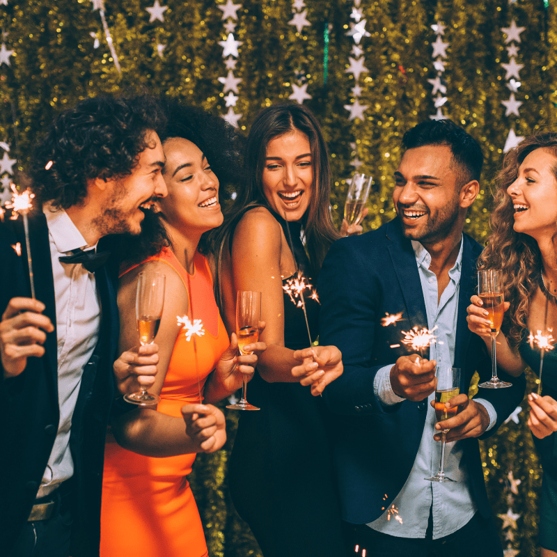 Freunde mit Sekt und Wunderkerze bei einer Silvester Party